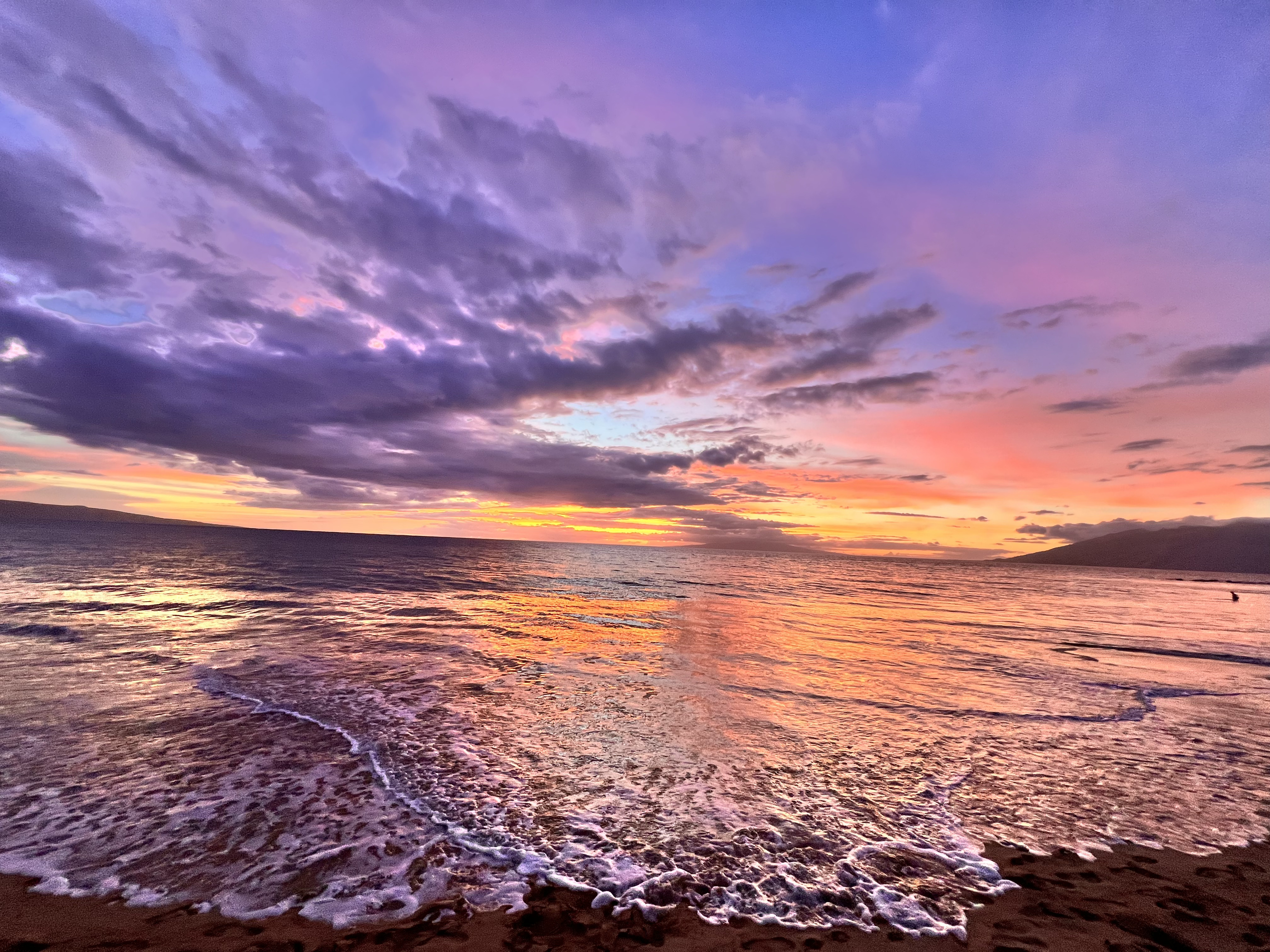 Vibrant sunset over Keawakapu Beach with purple clouds and golden reflections on the water