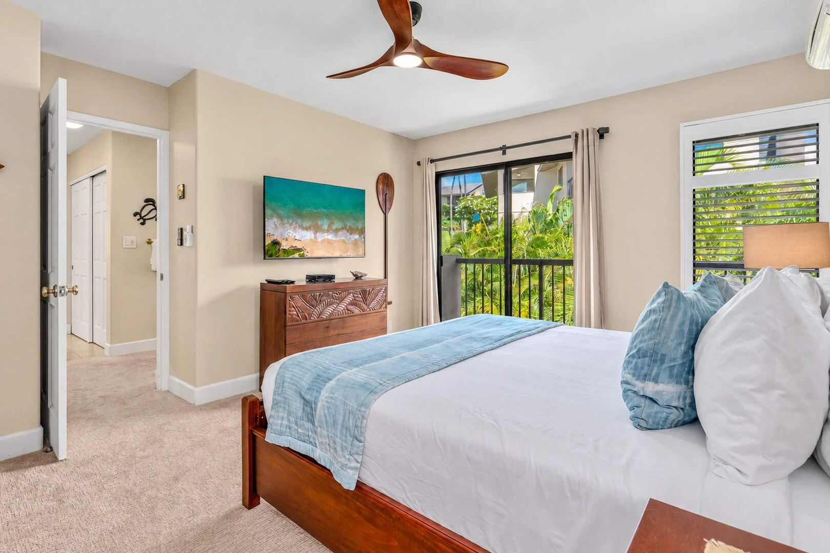 Bedroom with wall-mounted TV and private balcony over tropical gardens
